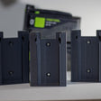Drie Festool accuhouders op een rij met een Festool accu op de achtergrond