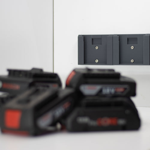Twee Bosch accuhouders aan de muur met Bosch 18V accu's op de voorgrond