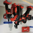 Milwaukee M18 machines hangend in gereedschaphouders onder een plank, met Gadgets4tools-bordje