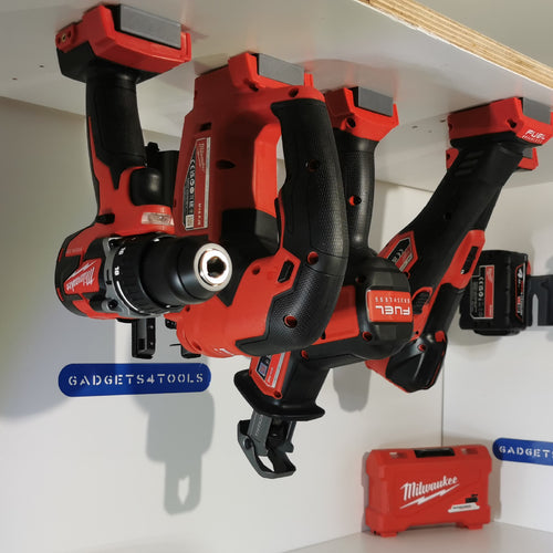 Milwaukee M18 machines hangend in gereedschaphouders onder een plank, met Gadgets4tools-bordje