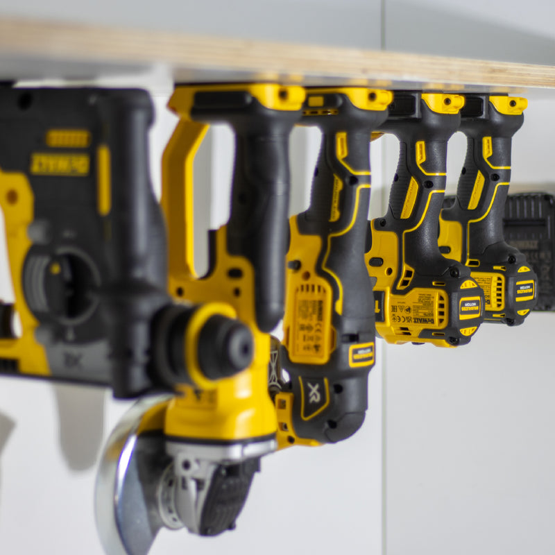 Rij DeWalt machines hangend in gereedschaphouders onder een werkbankplank