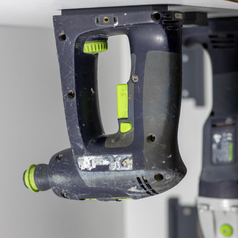 Festool machine hangt ondersteboven in een gereedschaphouder onder een plank