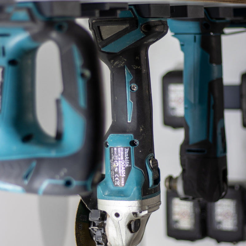 Makita haakse slijper en andere machines hangend in wandhouders onder een werkbankplank