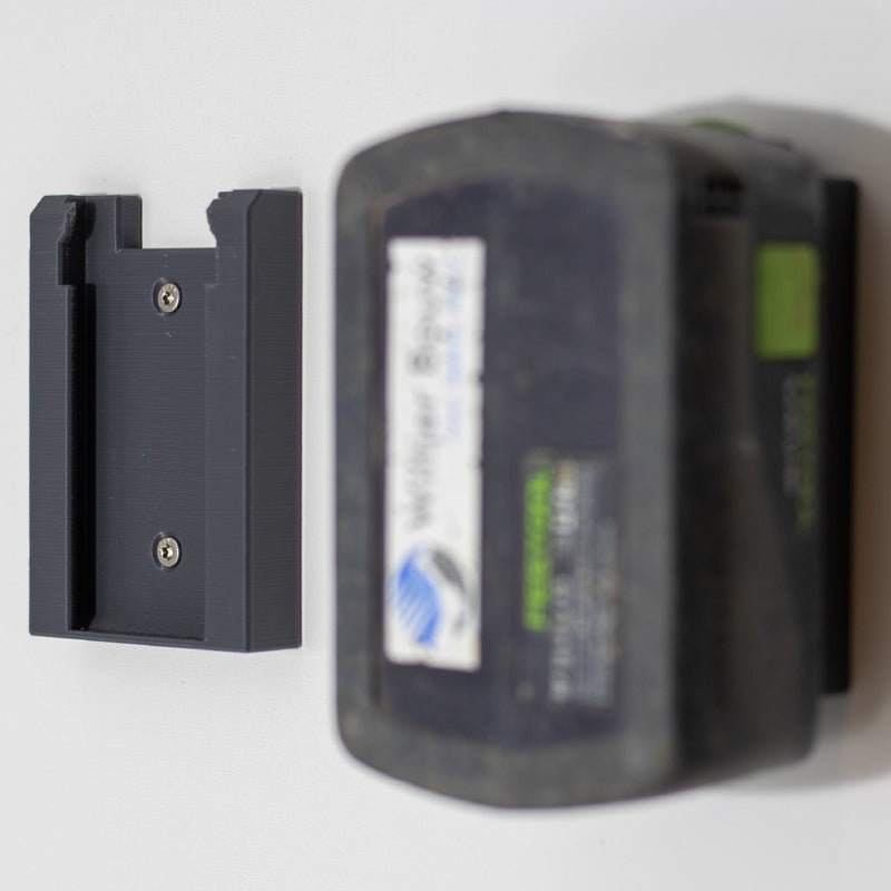 Lege Festool accuhouder aan de muur naast een opgehangen Festool 18V accu